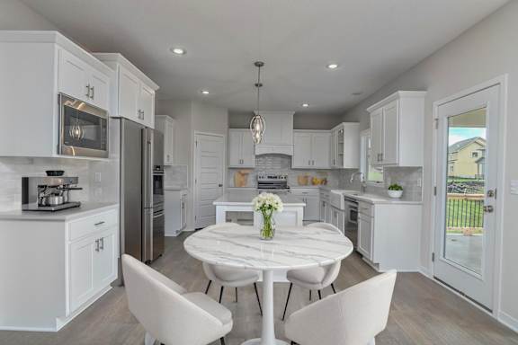 A white kitchen with a table and chairs in the middle.