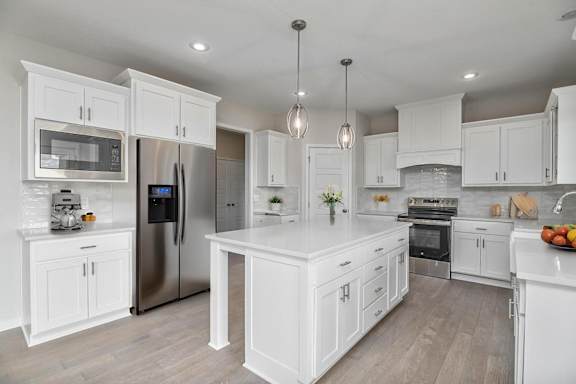 A modern kitchen with white cabinets and stainless steel appliances.
