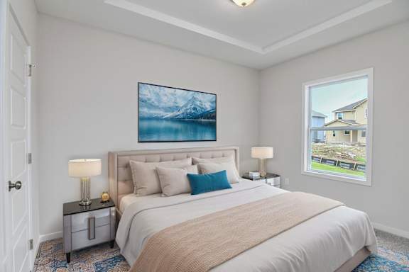 A bedroom with a large bed, a painting above it, and a window showing a house.