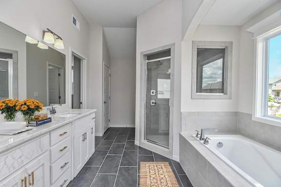 A bathroom with a tub, sink, and mirror.