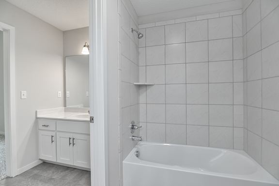 A white bathroom with a tub, sink, and mirror.