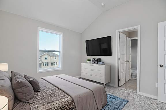 A bedroom with a large bed and a television on the wall.