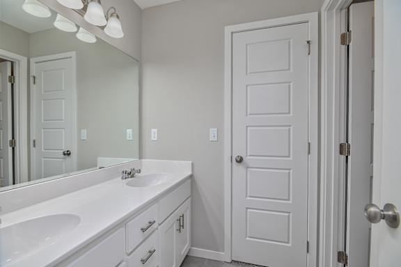 A white bathroom with a sink and mirror.