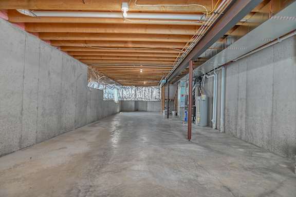 A long, empty hallway with concrete walls and a wooden ceiling.