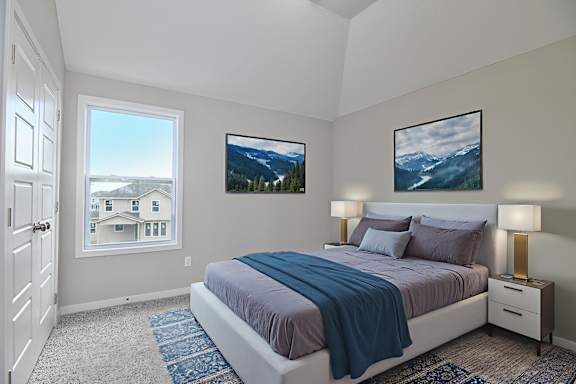 A bedroom with a large bed and two pictures on the wall.