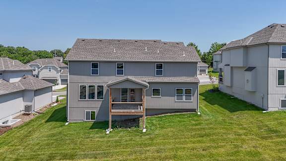 A house with a grey roof and a deck in the front yard.
