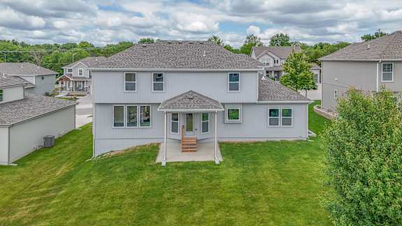 A white house with a brown roof and a green lawn.