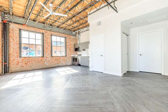 A large empty room with a brick wall and wooden ceiling.