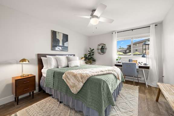 A bedroom with a bed, desk, and chair.