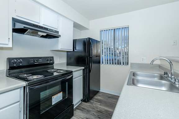 A black stove and refrigerator in a white kitchen.