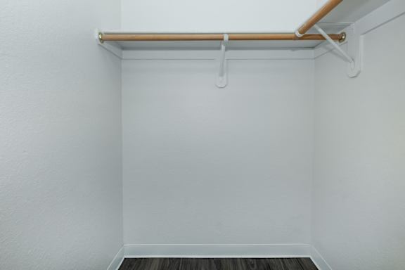 A white wall with a shelf and a wooden floor.