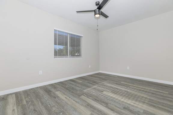 A room with a ceiling fan and a window with blinds.