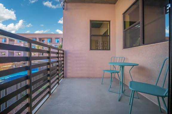 A balcony with a table and chairs overlooking a pool.