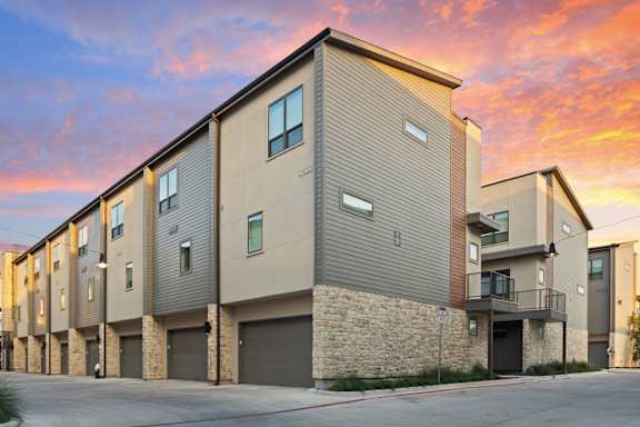 A modern apartment building with a sunset sky in the background.