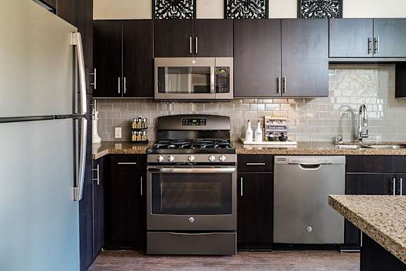 A modern kitchen with dark wood cabinets and stainless steel appliances.