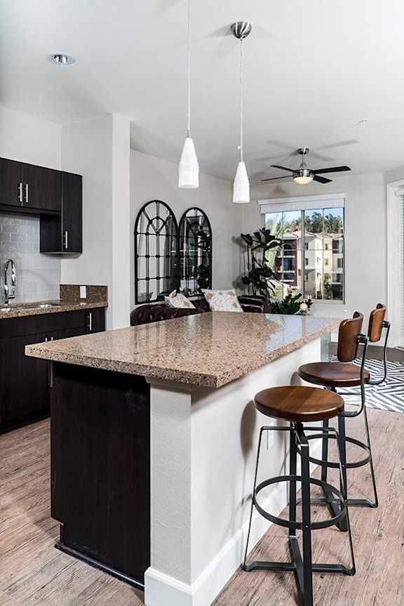 A kitchen with a bar area featuring a granite countertop and bar stools.