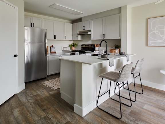 A kitchen with a white island and two chairs.