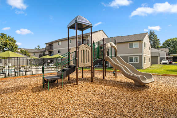 A playground with a slide, swings, and a tower structure.