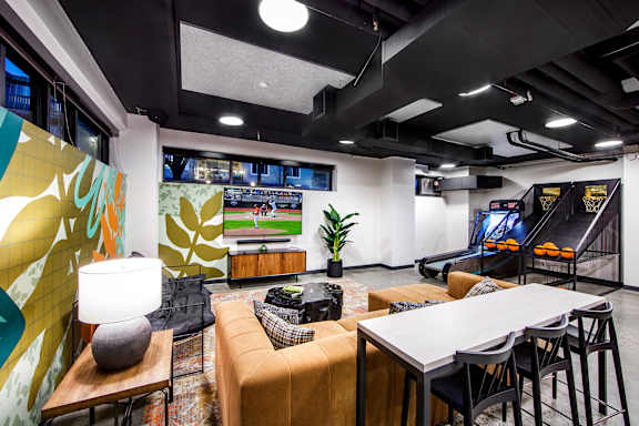 A modern office space with a yellow and green wall mural, a white table, and a black bean bag.
