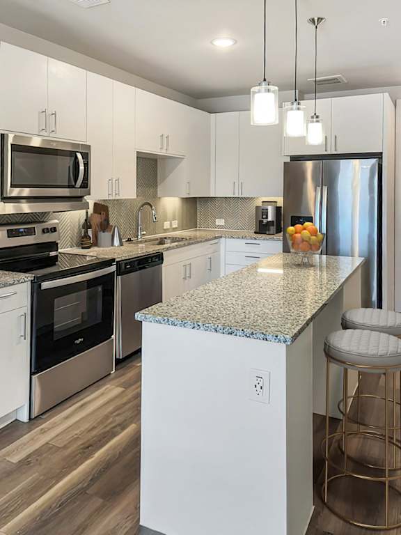 A kitchen with a granite countertop and stainless steel appliances.