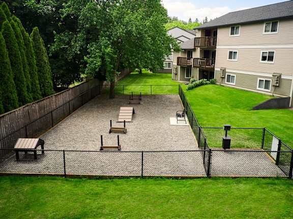 A backyard with a fence, benches, and a trampoline.