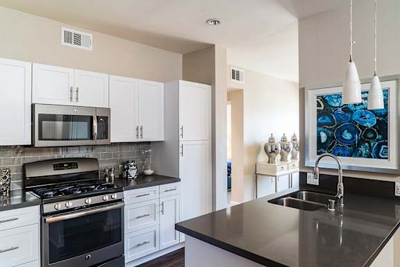 A modern kitchen with a black countertop and white cabinets.