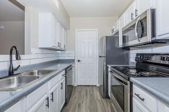 A kitchen with white cabinets and stainless steel appliances.