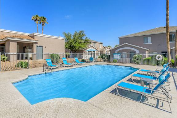 A swimming pool with blue water and lounge chairs.
