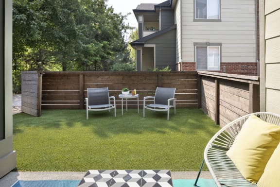 a backyard with a wooden fence and a patio with two chairs and a table