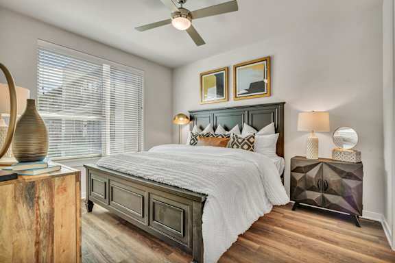 A bedroom with a large bed, overhead ceiling fan, and a wooden headboard.