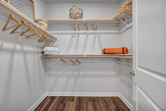 A white closet with wooden hangers and a basket on top.