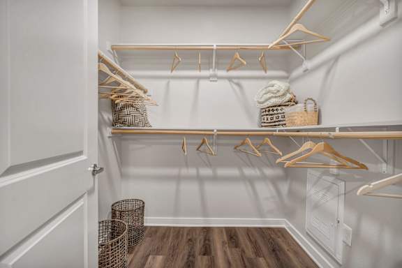 A white closet with wooden hangers and baskets.