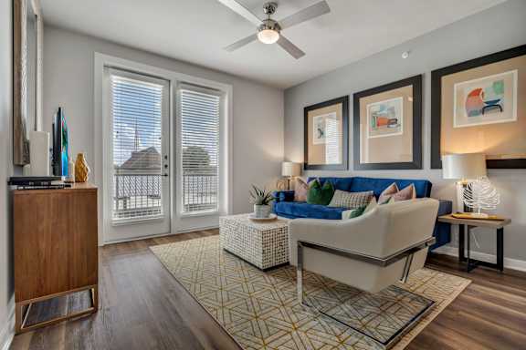 A living room with a couch, ceiling fan, a television, and a rug.