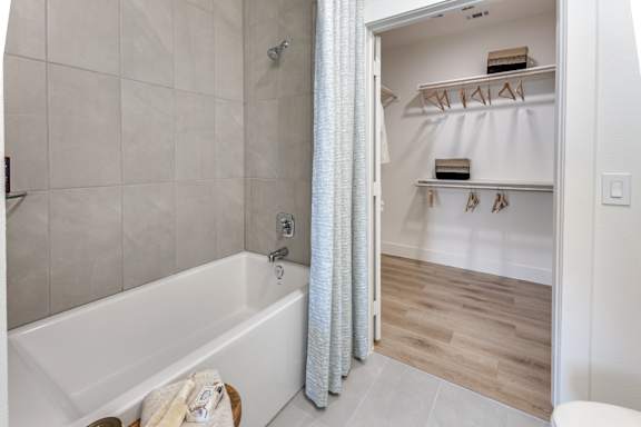 A white bathroom with a white tub and a white walk in closet.