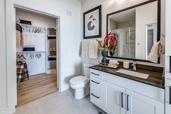 A bathroom with a toilet, sink, and mirror.