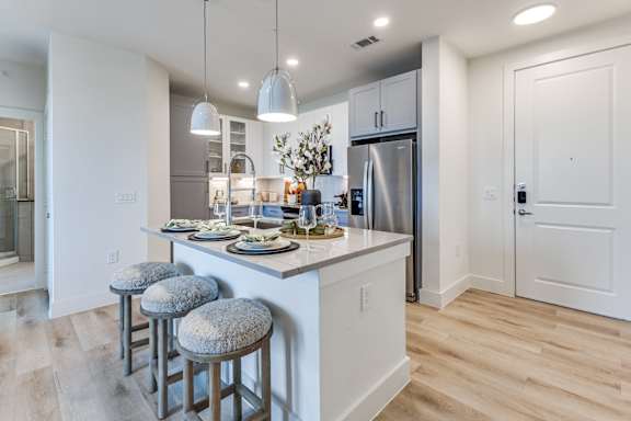 A kitchen with a bar stool and a refrigerator.