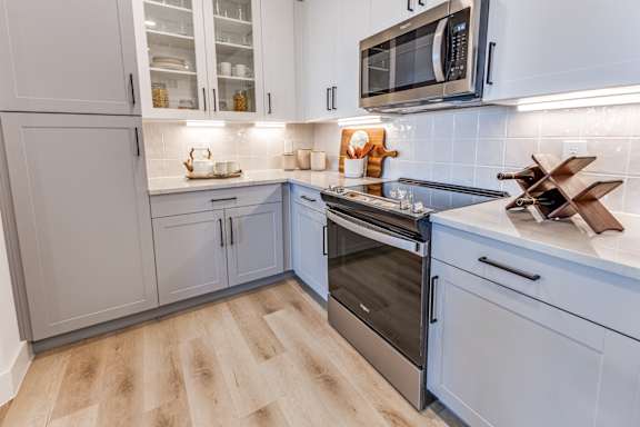 A kitchen with a wooden floor and a stainless steel oven.
