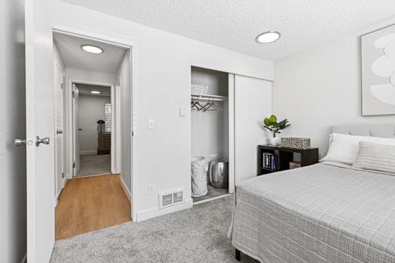 A bedroom with a bed, nightstand, and closet.
