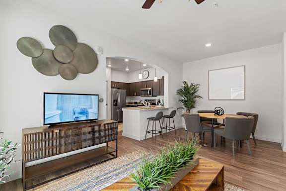 A modern living room with a television, a bar, and a dining area.
