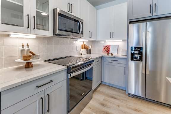 A modern kitchen with a stainless steel refrigerator, microwave, and oven.