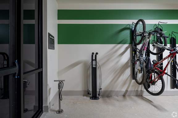 A bicycle is hanging on a wall next to a bike rack.