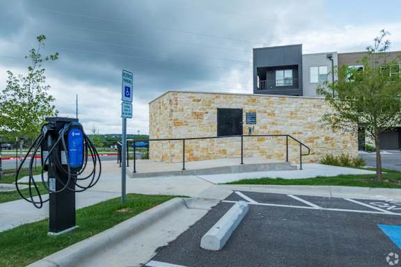 A parking lot with a building and a blue electric car charging station.