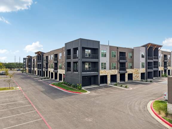 A parking lot in front of a modern apartment building.