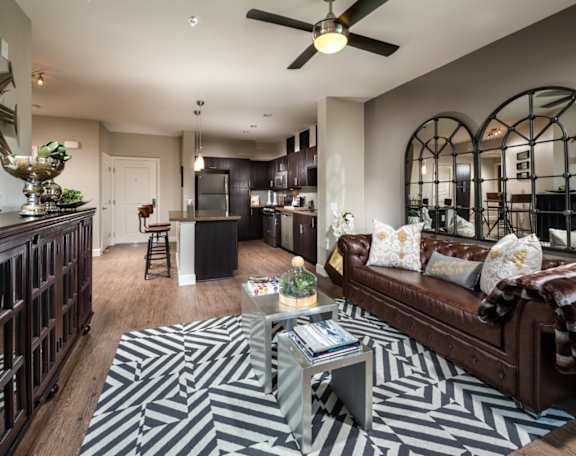 A living room with a black and white rug and a brown couch.