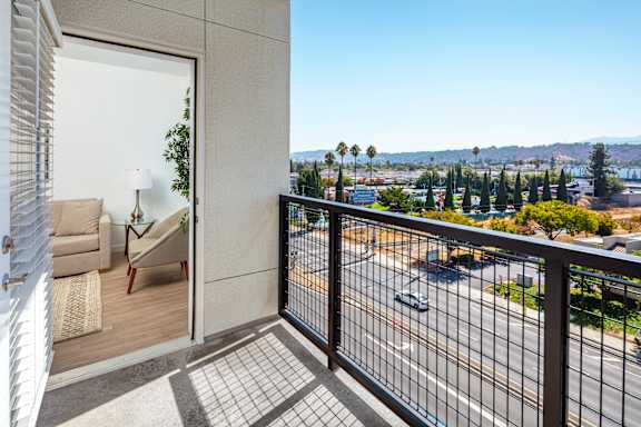 A balcony with a view of a street and trees.