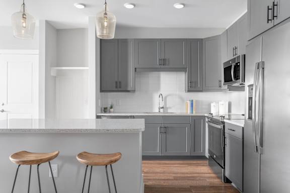 A modern kitchen with a white countertop and grey cabinets.