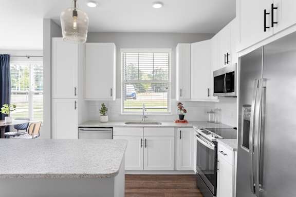 A modern kitchen with white cabinets and stainless steel appliances.