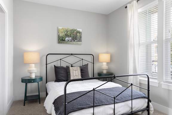 A bedroom with a black metal bed frame and a white bedspread.