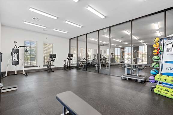 A gym with a variety of equipment including treadmills, weights, and exercise machines.