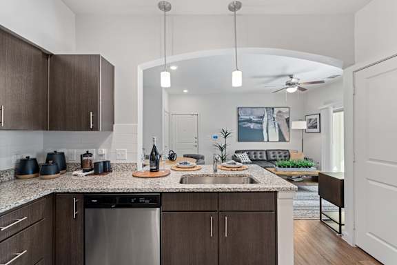A modern kitchen with a large island and a dining area in the background.